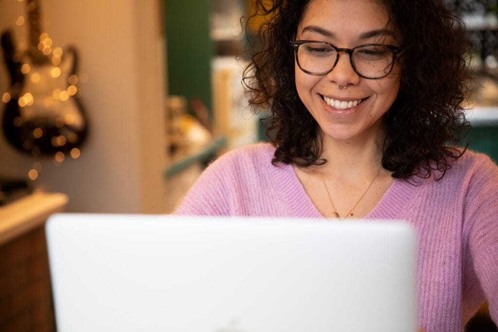 person-wears-glasses-and-smiles-at-their-laptop
